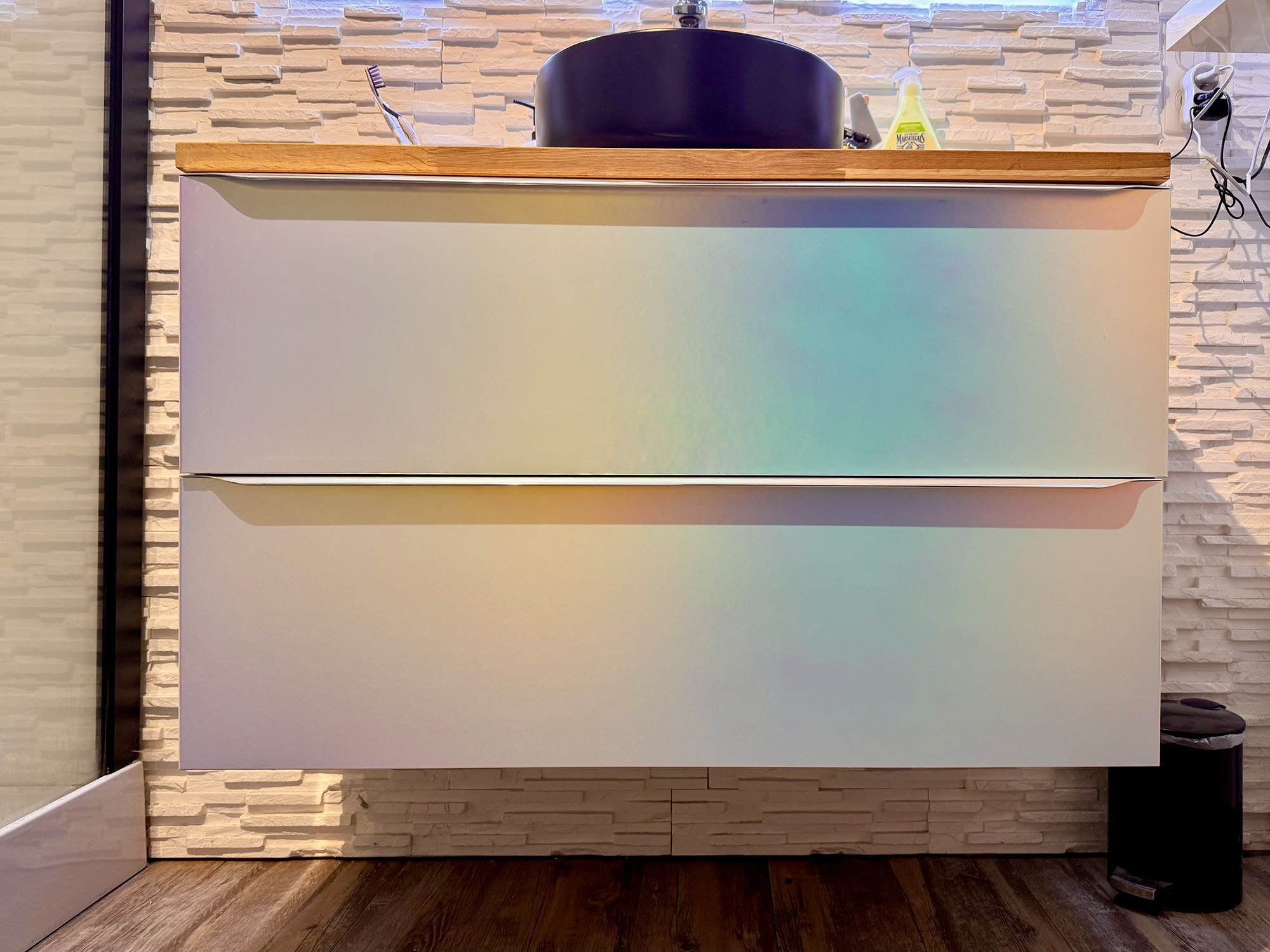 Initialement beige, ce meuble de salle de bain adopte désormais une finition irisée aux nuances nacrées grace au revêtement métallique Aurora. Chaque rayon de lumière révèle de nouvelles couleurs.