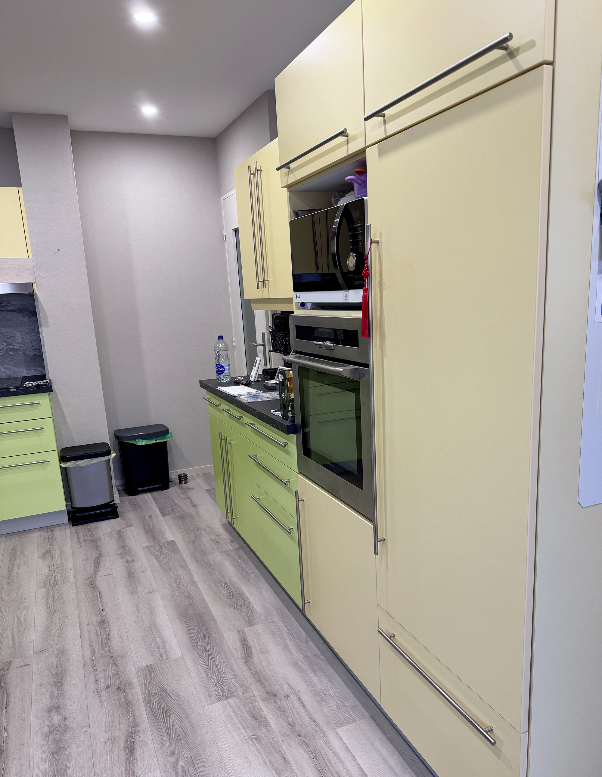Avant sa transformation, cette cuisine associait des façades vert anis et jaune pâle, un style très marqué qui ne correspondait pas aux attentes de son nouveau propriétaire. Le covering architectural lui a offert une toute nouvelle identité, plus chaleureuse et intemporelle.