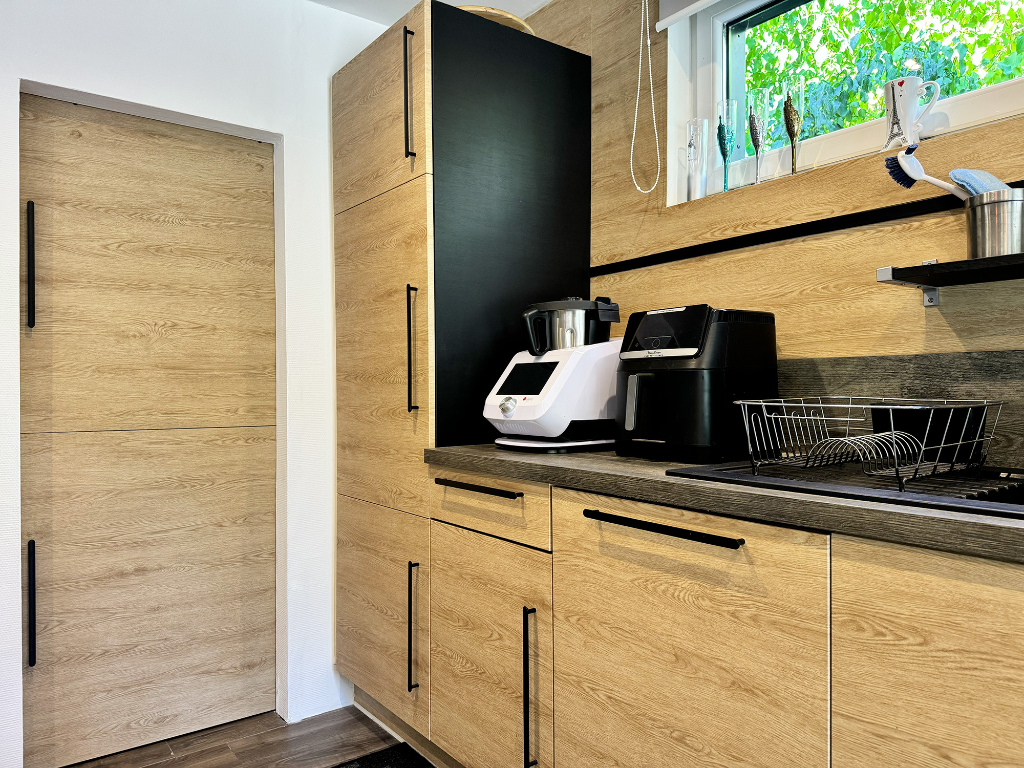 Un décor bois naturel qui réchauffe immédiatement la pièce, associé à des éléments noirs texturés pour une ambiance contemporaine et élégante.